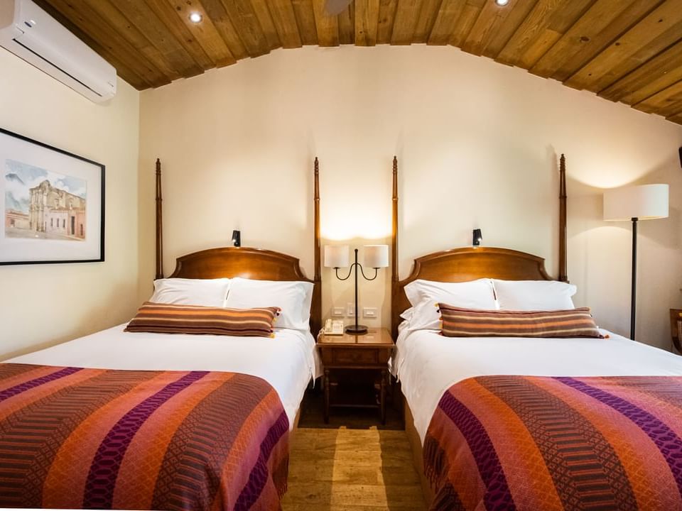 Nightstand by two double beds in Premium Garden with wooden floors at Porta Hotel Antigua