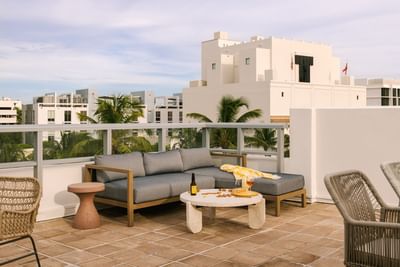 Terrace lounge with an L-shaped sofa, wicker chairs, and city views from Kenmore Village Hotel, Art Deco district of Miami