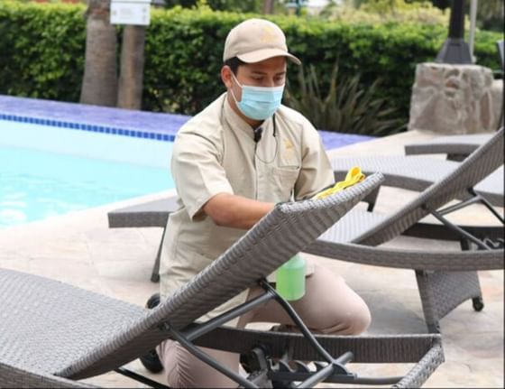 Staff cleaning sunbeds by the pool at Hotel Coral y Marina