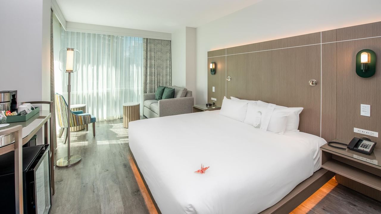 Modern hotel room interior with large bed, couch, and amenities.