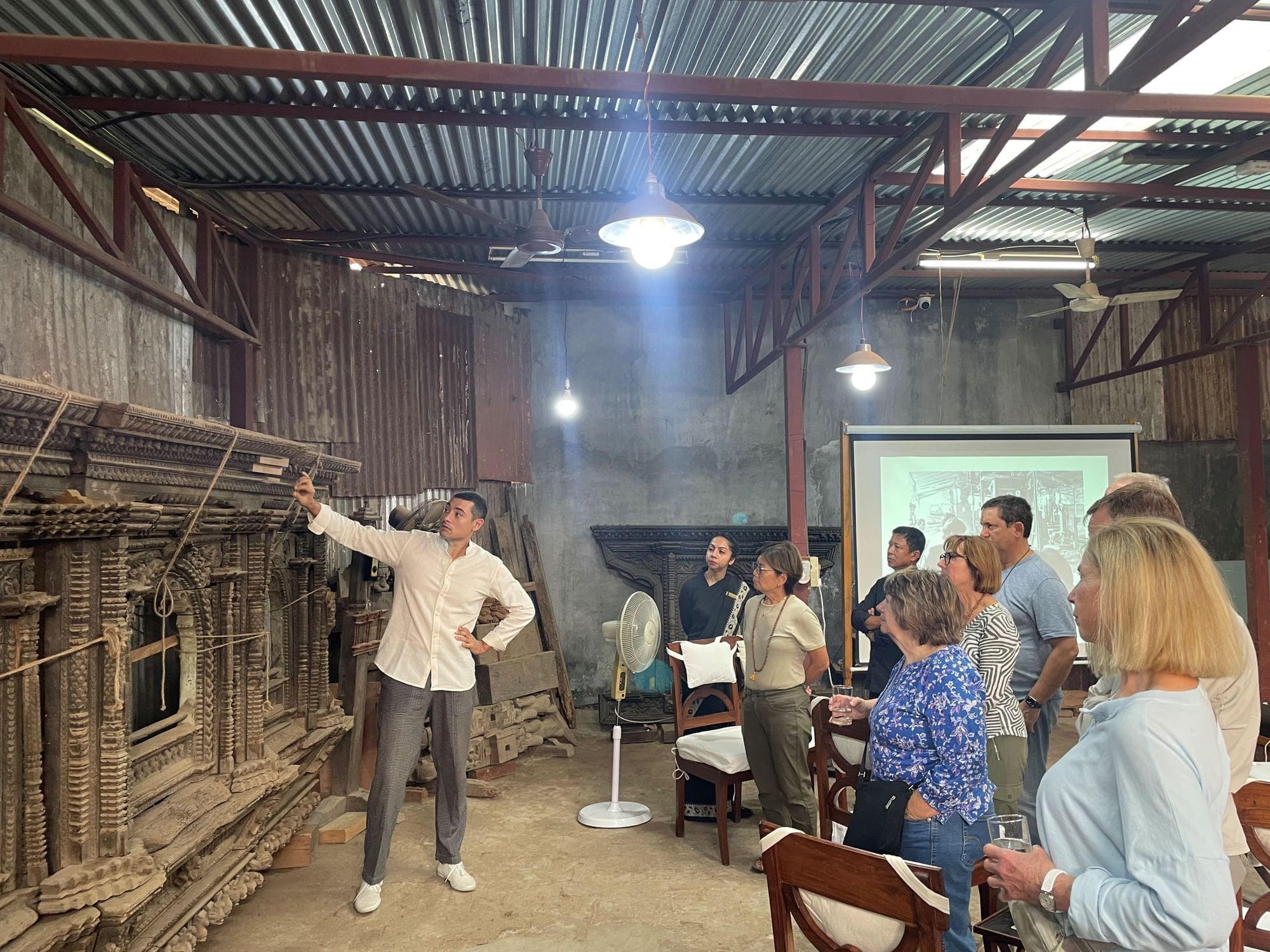 Group of people attentively listening to a speaker in a workshop with rustic wooden artifacts near Dwarika's Hotel Kathmandu