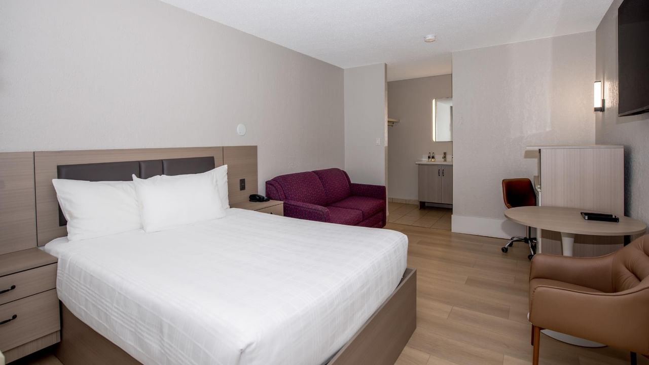 Guest room at Coast Red Deer Hotel with queen bed, seating area and sofa