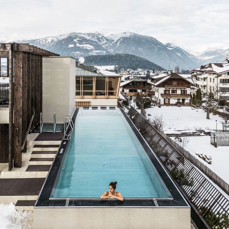 Woman in outdoor rooftop pool with snowy mountains