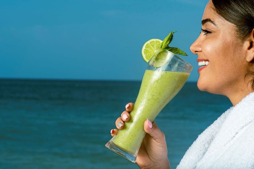 Close-up of a lady having an Avocado Smoothie by sea at Hotel Isla Del Encanto