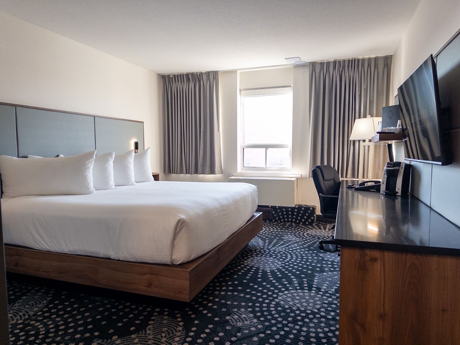Elegant bedroom with king-sized bed and office area at Carriage House Hotel & Conference Centre in Calgary.