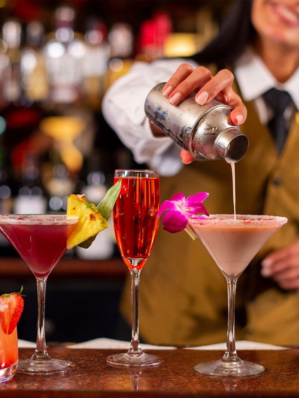 Bartender pouring drink into glass among colorful array of tropical cocktails in Randolph's Bar & Lounge at Warwick New York