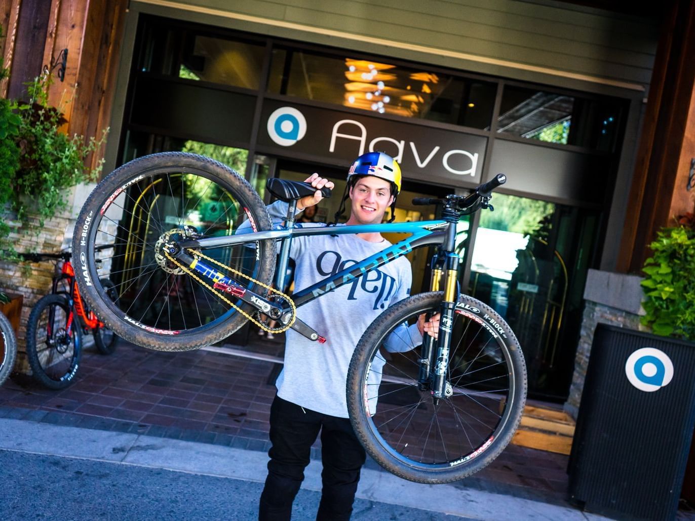 man holding mountain bike in front of aava whistler hotel