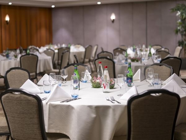 Elegantly set dining tables with glasses, napkins, and bottles at Warwick Grand-Place Brussels.