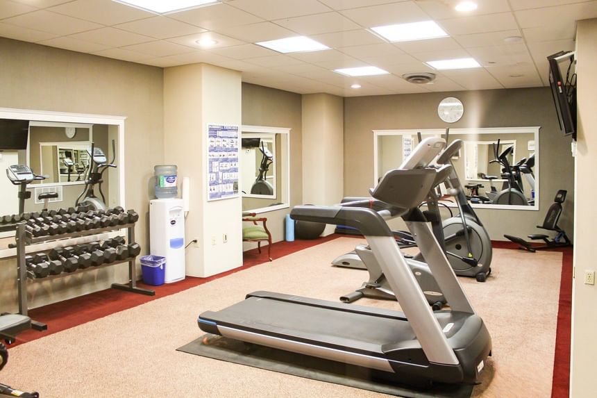Treadmill by stationary exercise bikes under square ceiling lights in a bright fitness room at Rodd Charlottetown Hotel