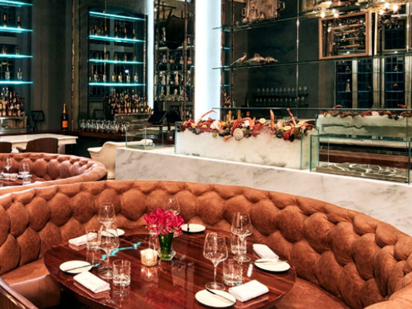 Blueblood Steakhouse with tufted brown banquettes, set tables, and a bar area near Hotel X Toronto