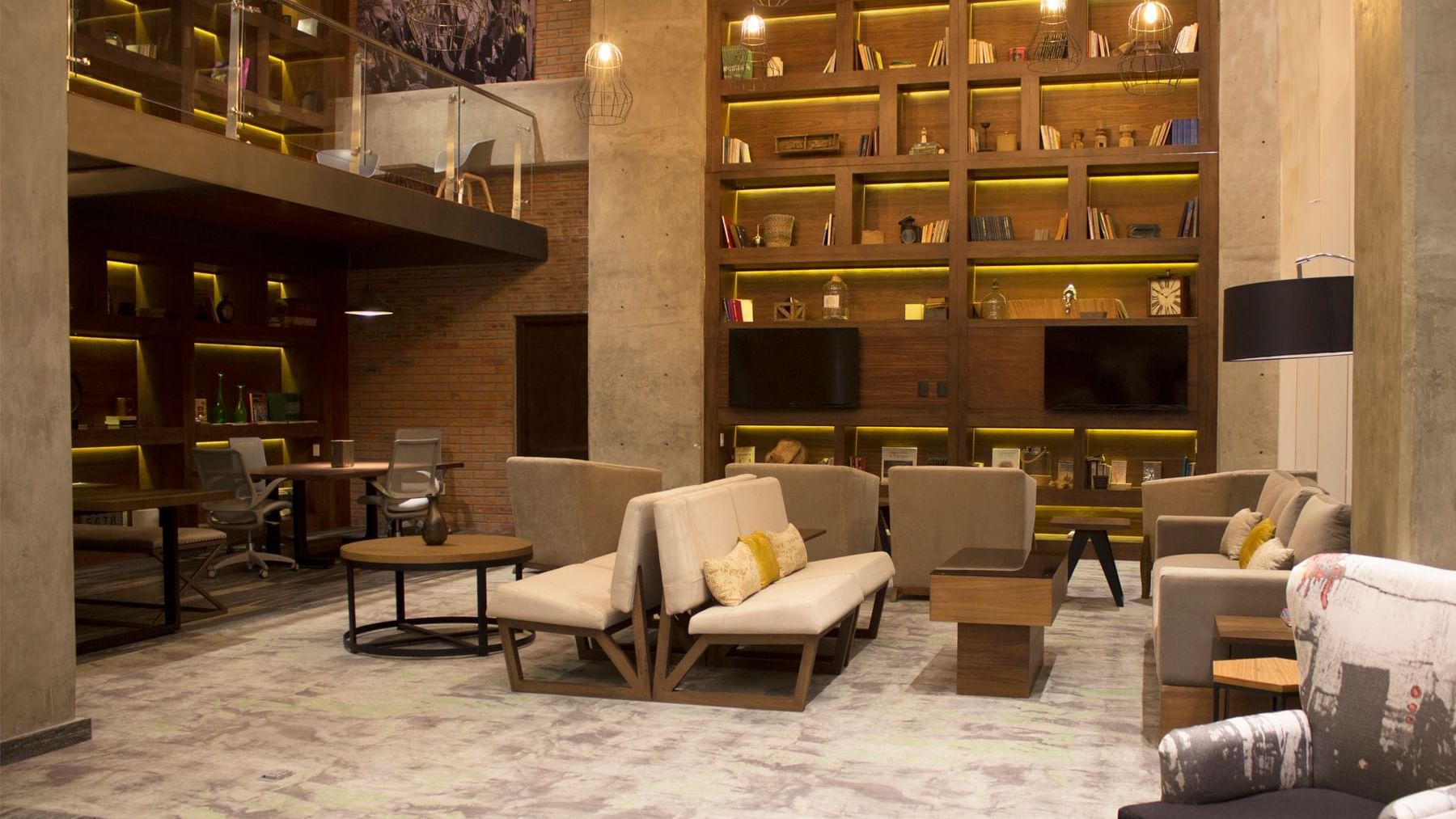 Elegant lobby area with large book shelves at Fiesta Inn Suites Aeropuerto del Bajío