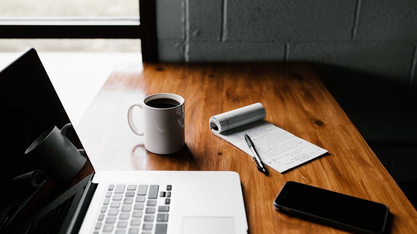 Laptop, notebook & a coffee mug on a desk at Sunway Lagoon