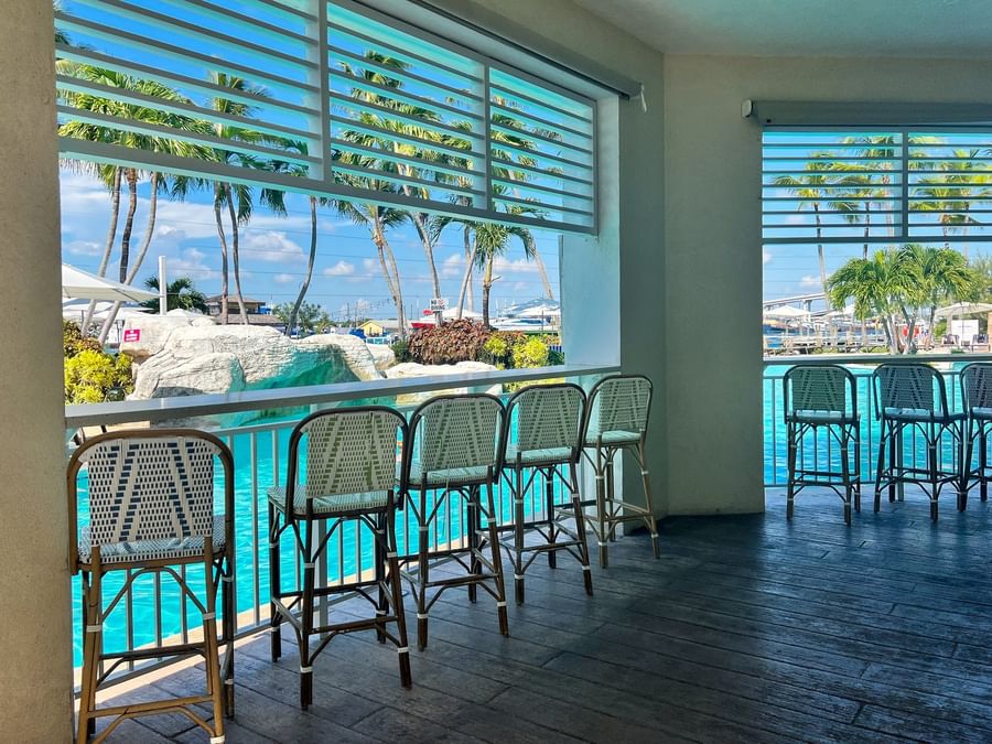 Woven bar stools by a white counter under louvers in Chickcharnie's Pizzeria & Grille at Warwick Paradise Island Bahamas