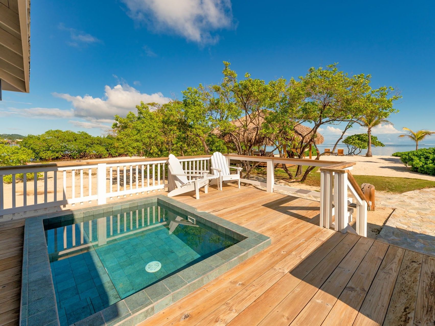 Outdoor deck with a plunge pool and white chairs in the Deluxe Beach View Villa at Barefoot Cay Resort & Marina