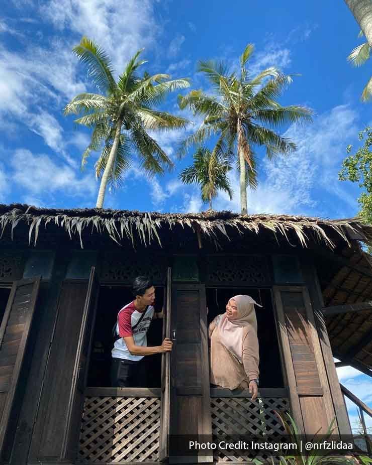 A couple was taking a picture with the traditional Malay house at Kampung Agong - Lexis Suites Penang