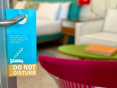 A photo of the do not disturb sign on the door with the electra deluxe room in the background