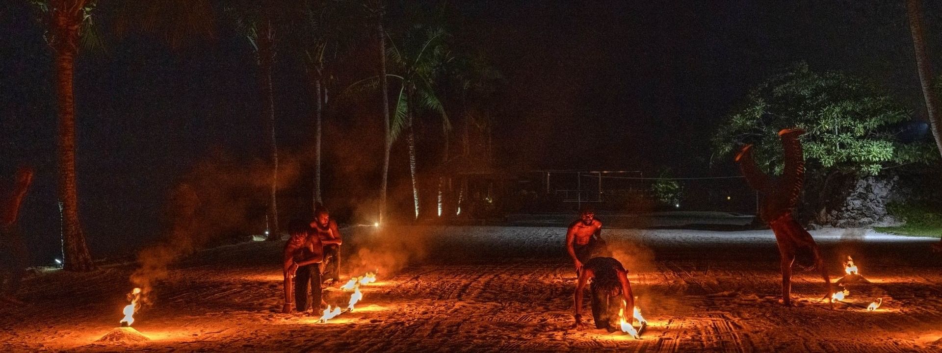 dynamic fire performance by dancers on the sand under a dark, starry sky at Warwick Hotel & Resort