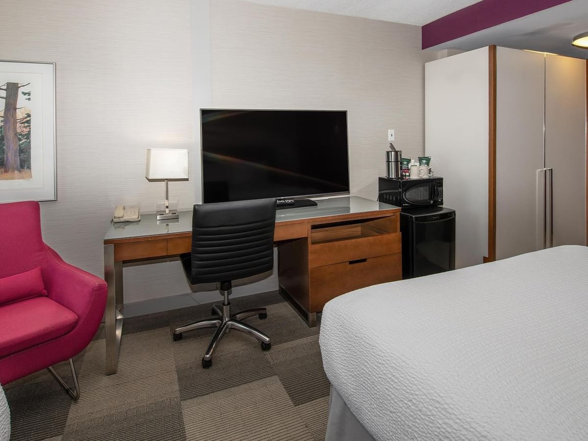 Guest room with two queen beds, work desk, flat-screen TV, and pink accent chair at Coast Prince George Hotel