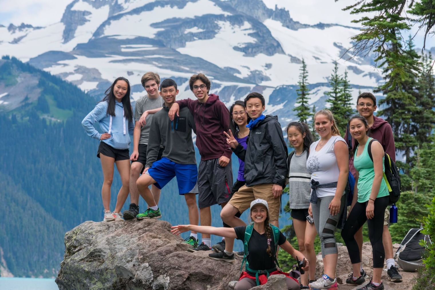 Group of hikers posing on a rock with a mountain backdrop near UniLodge Canada