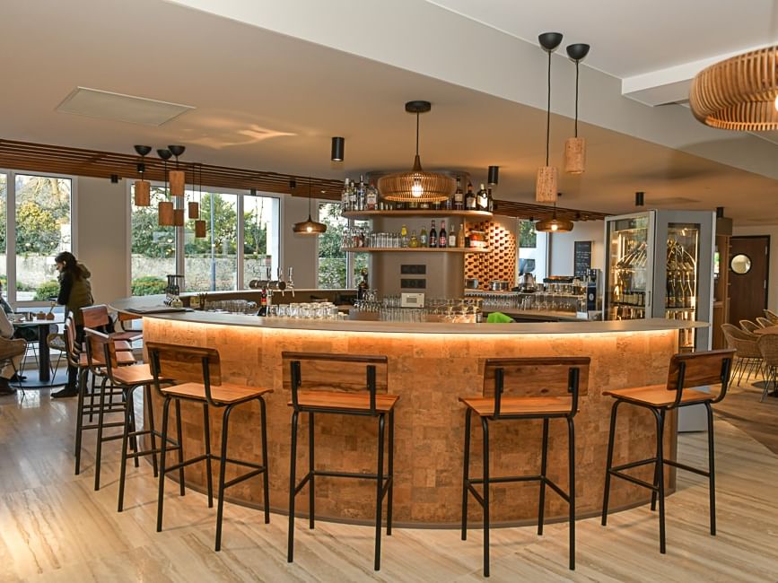 Bar élégant avec comptoir circulaire et tabourets en bois à l'Hôtel Rivella.