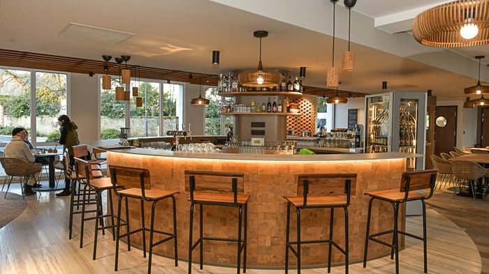 Bar élégant avec comptoir circulaire et tabourets en bois à l'Hôtel Rivella.