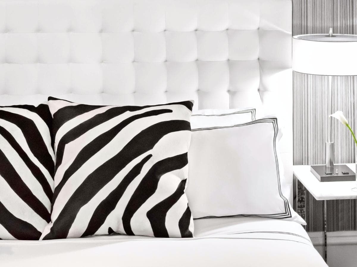 A close-up of a bed with white and zebra-print pillows