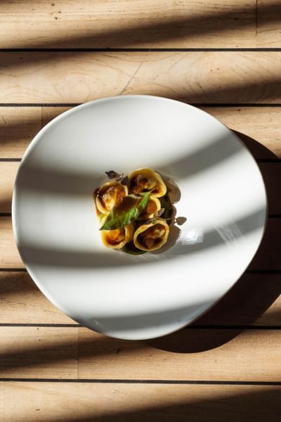 Plat élégant avec raviolis et sauce, éclairé par la lumière naturelle chez Grand Hotel Portovenere