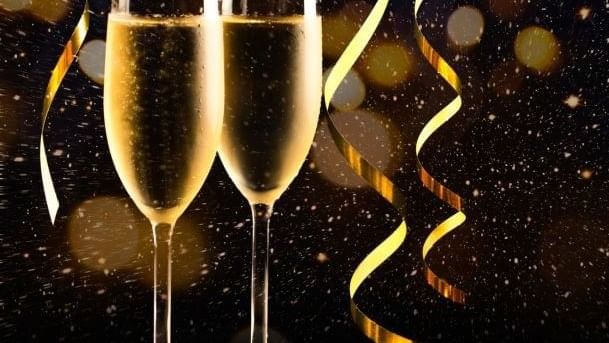 Deux flûtes de champagne avec des serpentins dorés sur fond festif scintillant pour célébrer la Saint-Sylvestre