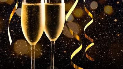 Deux flûtes de champagne avec des serpentins dorés sur fond festif scintillant pour célébrer la Saint-Sylvestre