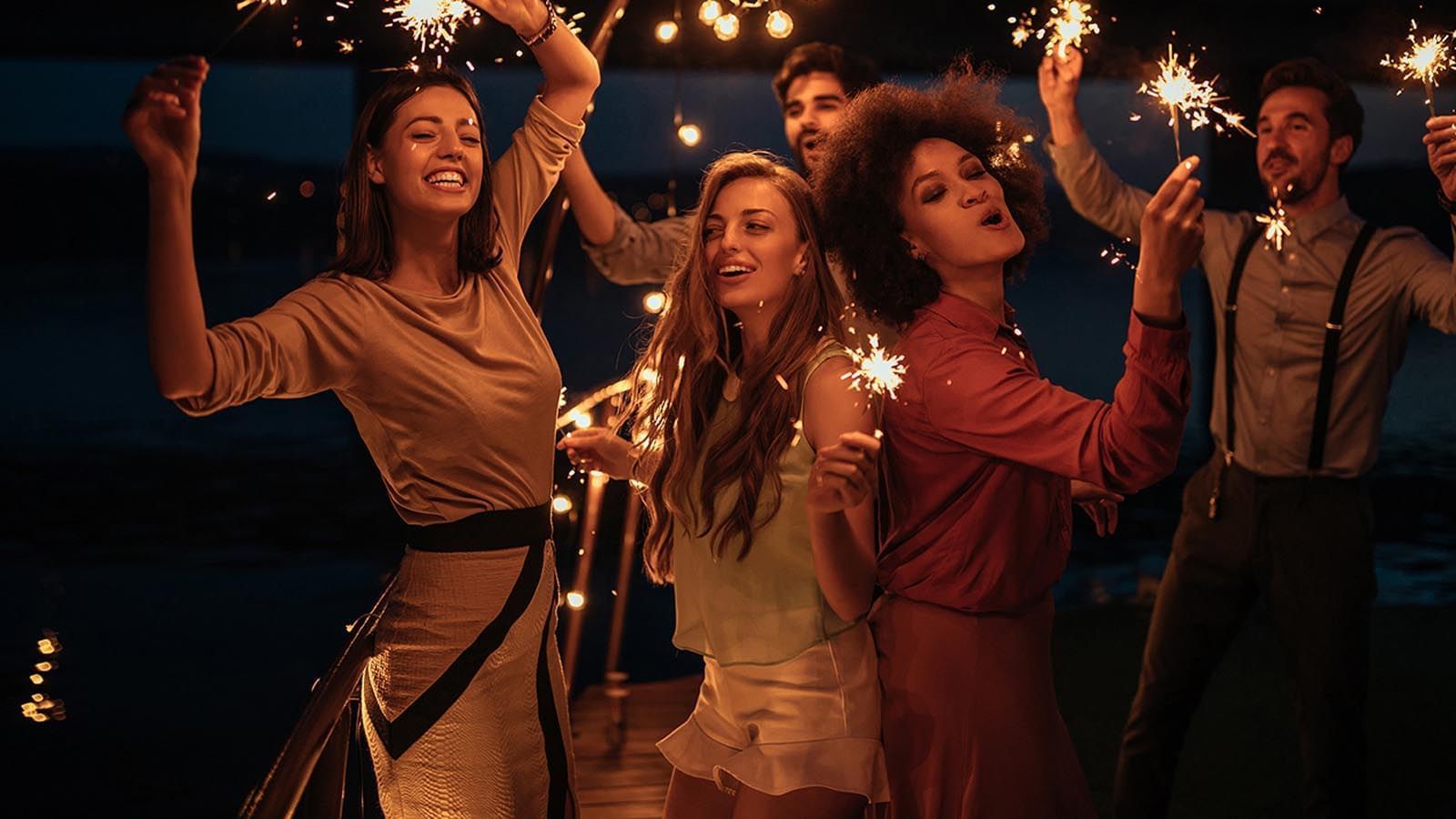 Group of people celebrating outdoors holding sparklers at night in Sofitel Brisbane Central