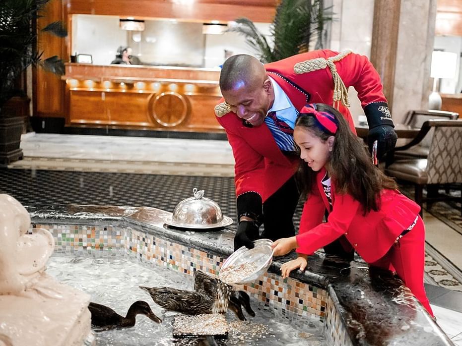 Concierge helping a girl feed the ducks at The Peabody Memphis