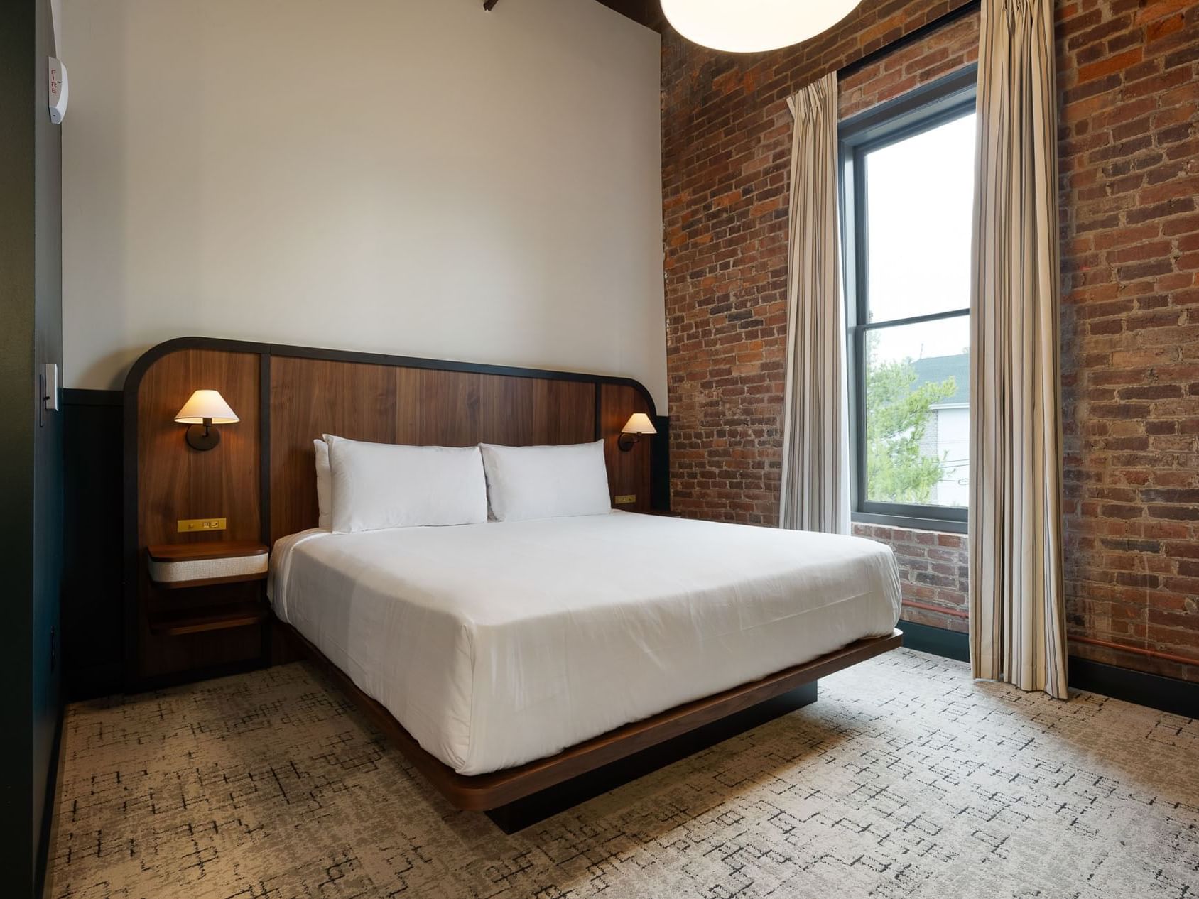 King Room with double bed, headboard, wall-mounted lamp and window at The Delegate Hotel