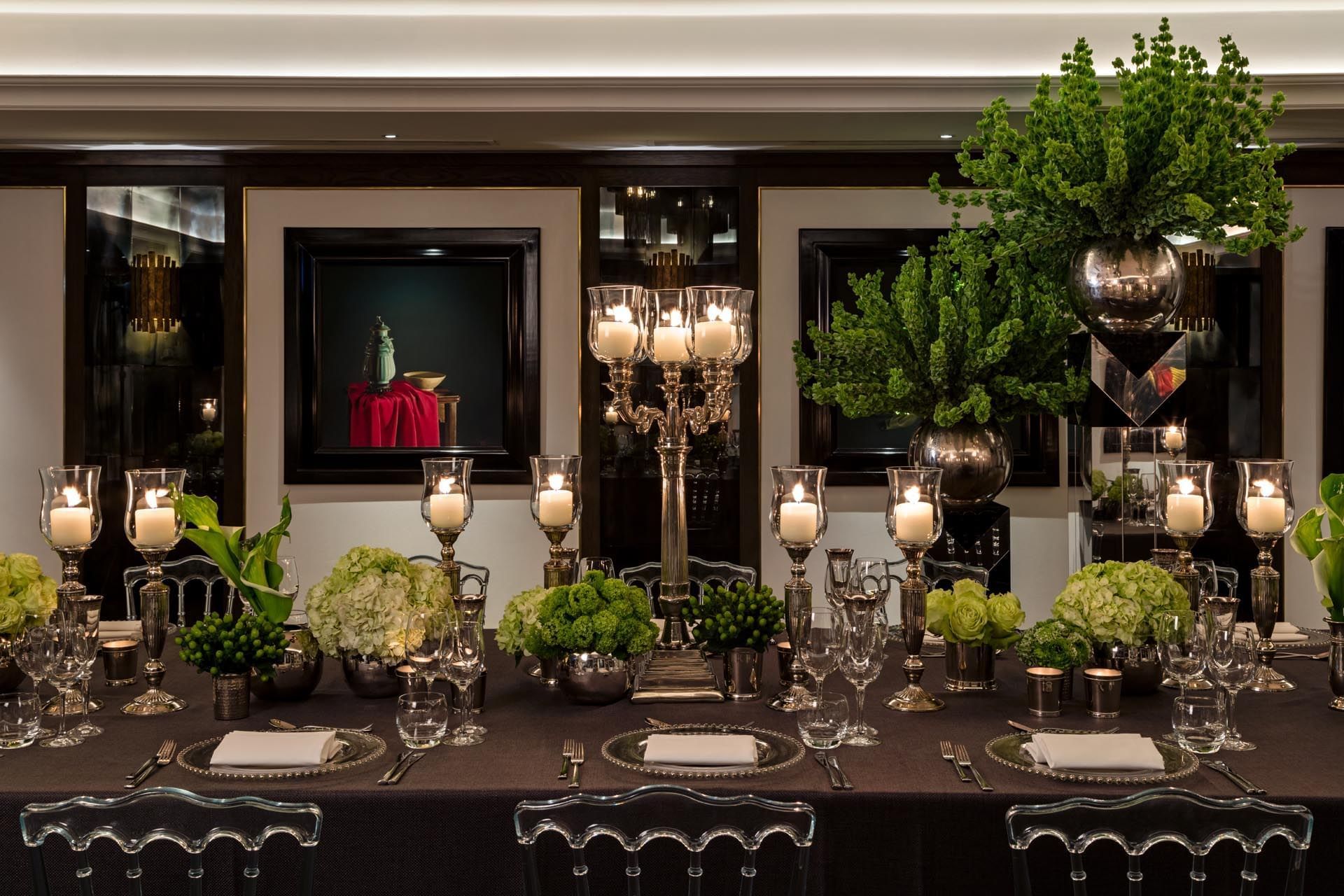 An elegantly set dining table with floral arrangements and candleholders at The May Fair Hotel London.