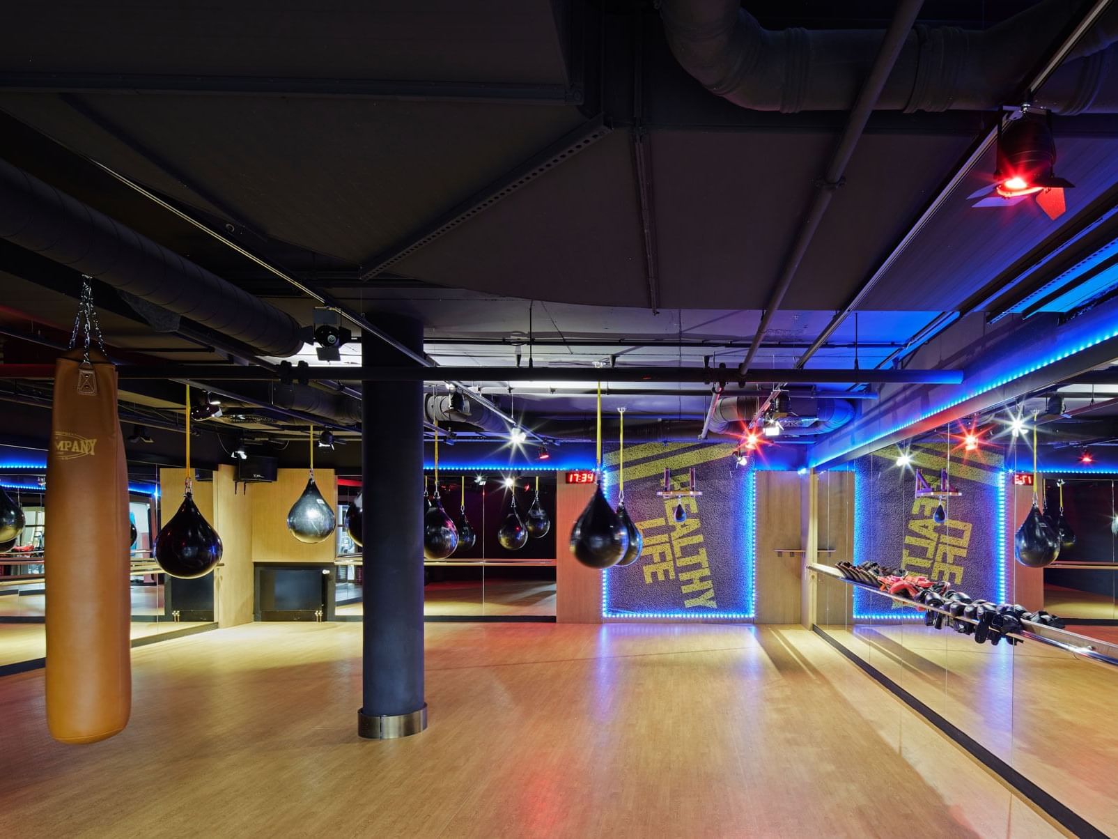 Modernes Fitnessstudio mit blauer Beleuchtung, schwarzen Boxsäcken und Holzboden – Titanic Chaussee Berlin.