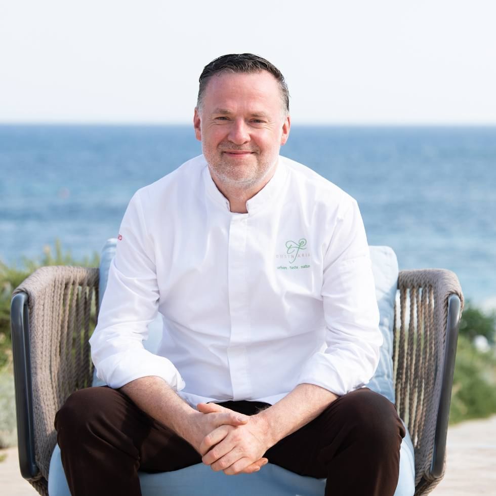 Chef Theodor Falser posing for a picture by the sea at Falkensteiner Resort Capo Boi