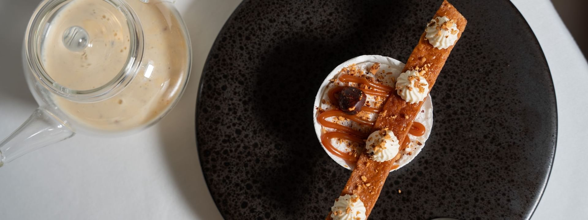 Gourmet dessert with caramel sauce on a dark plate served in Le Céladon at Hotel Westminster Paris