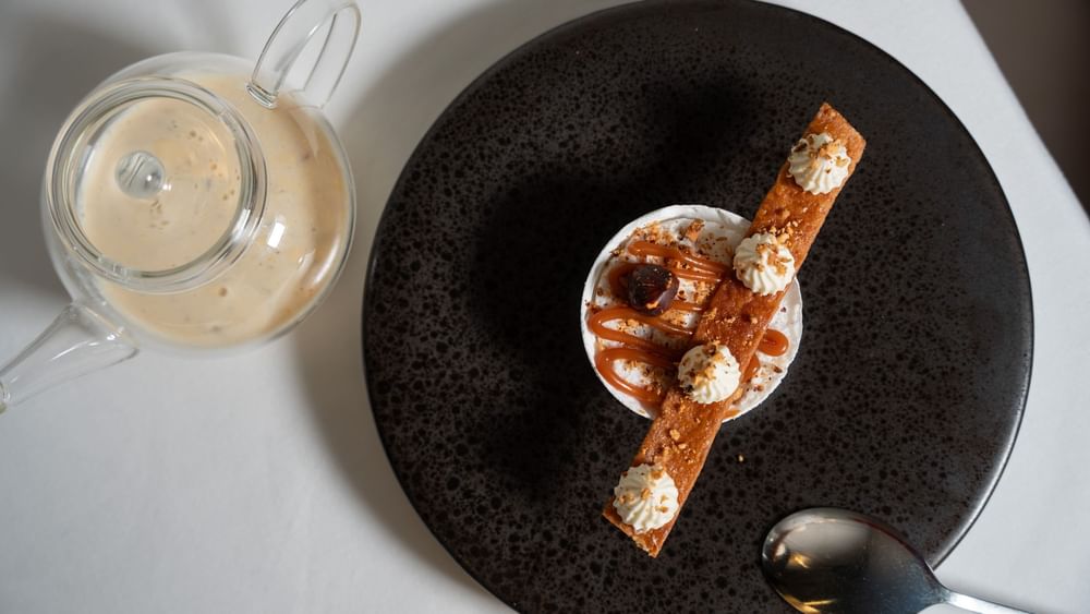 Gourmet dessert with caramel sauce on a dark plate served in Le Céladon at Hotel Westminster Paris