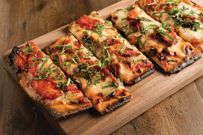 Pizza slices served on a wooden board at The Diplomat Resort