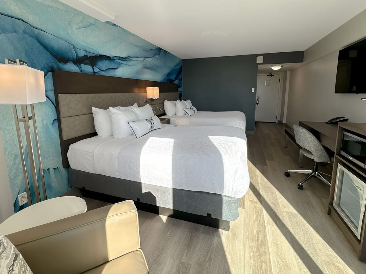 Hotel guestroom with two queen beds and a blue wall mural