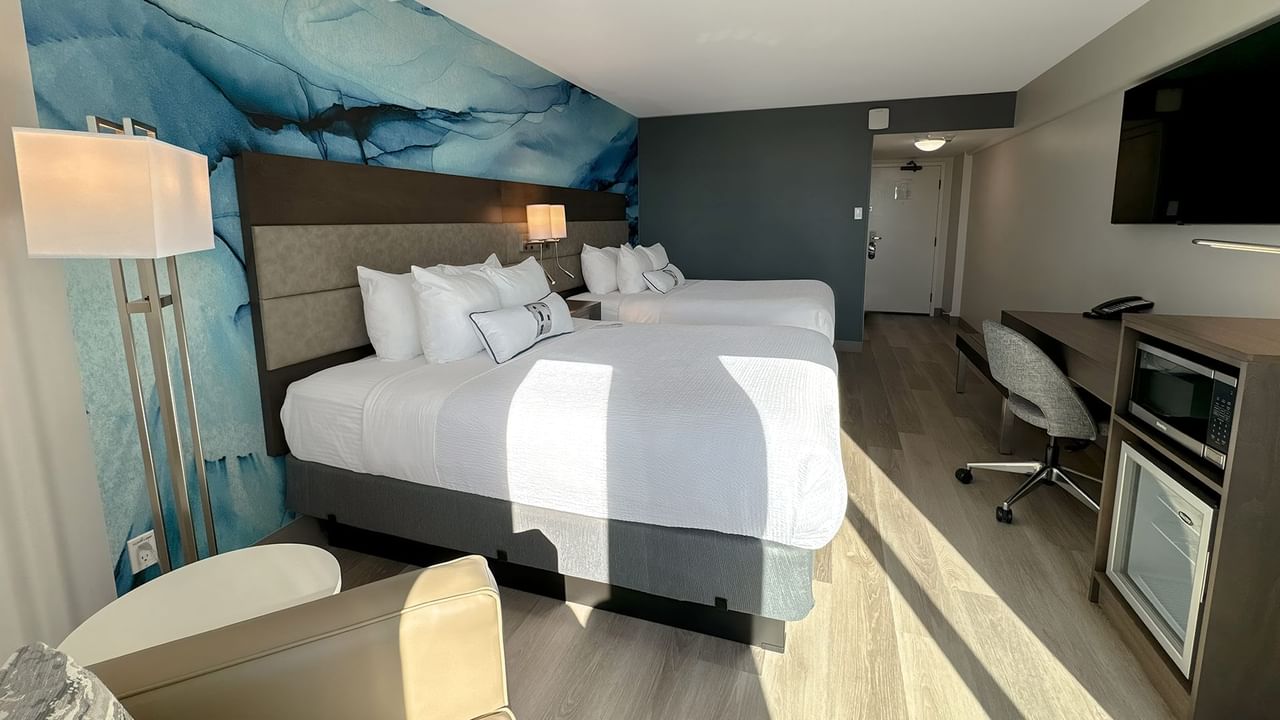 Hotel guestroom with two queen beds and a blue wall mural