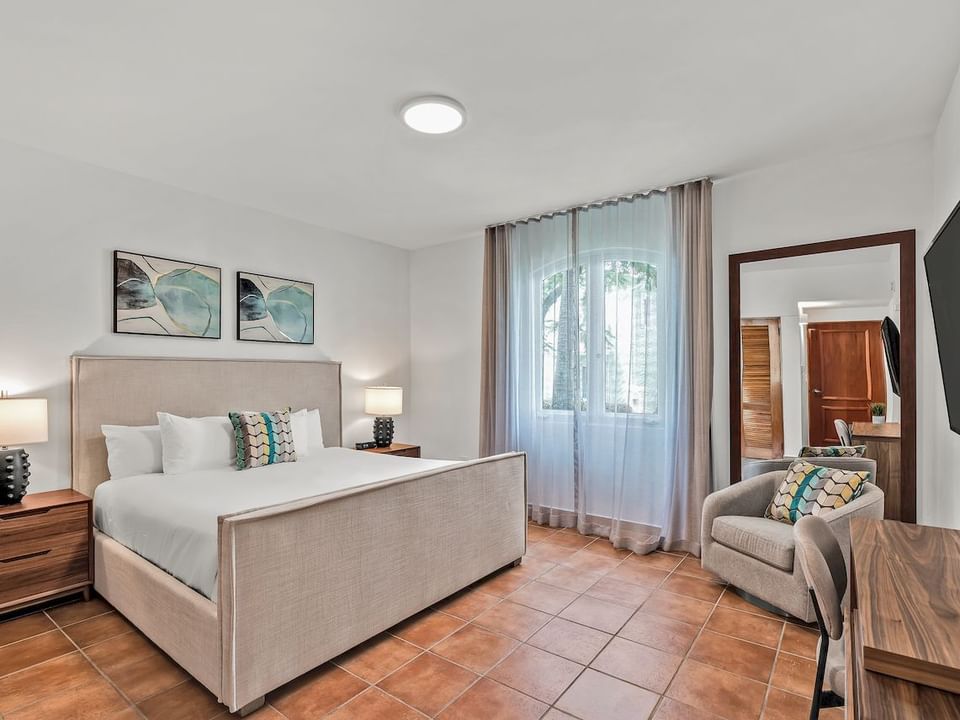Bed by the window and mirror behind the couch in Casitas Guest Room at Las Casitas Village