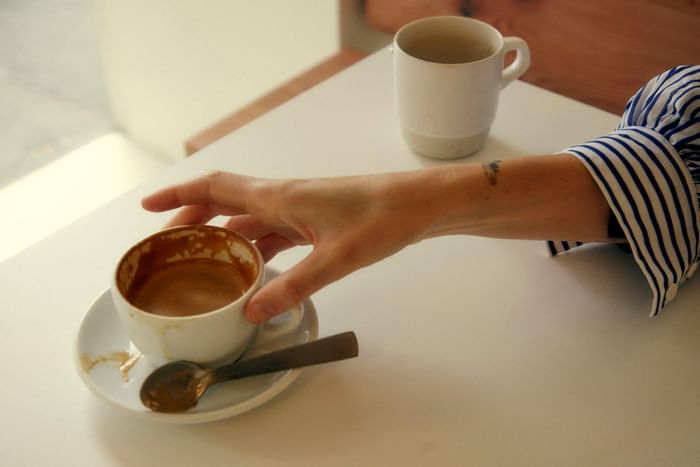 Woman holding a coffee cup at Hector’s Deli near The Kinson