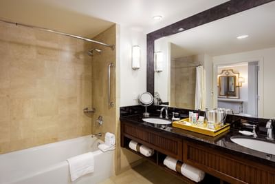 Luxurious bathroom in Standard King at Santa Barbara Inn, featuring a bathtub, double vanity, mirror, and elegant decor