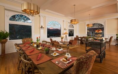 Manor hall spacious dining room with a long wooden table set with red placemats, plates and coffee cups at The Stanley Hotel