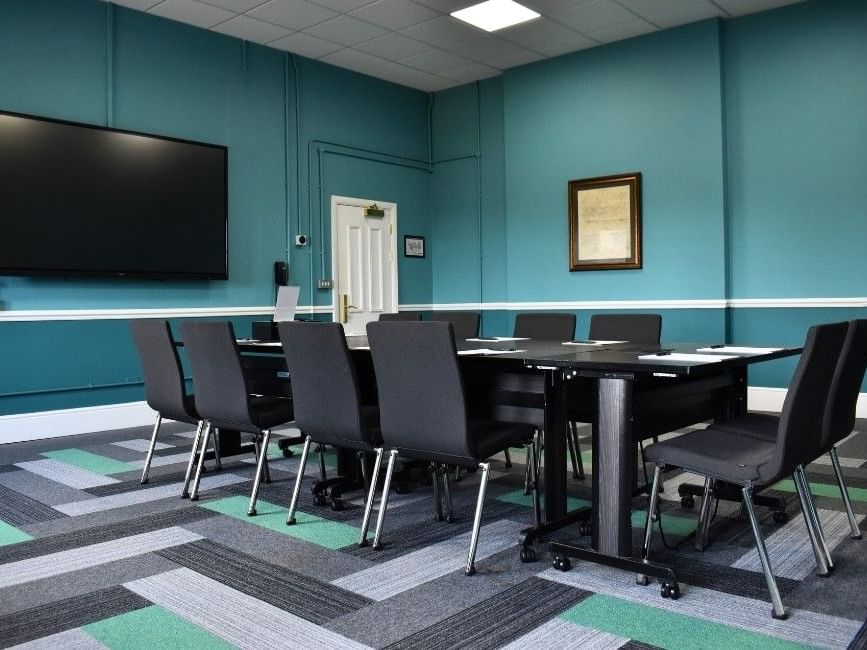Wylie event room with teal walls, large screen, and boardroom table at Easthampstead Park Hotel in Bracknell