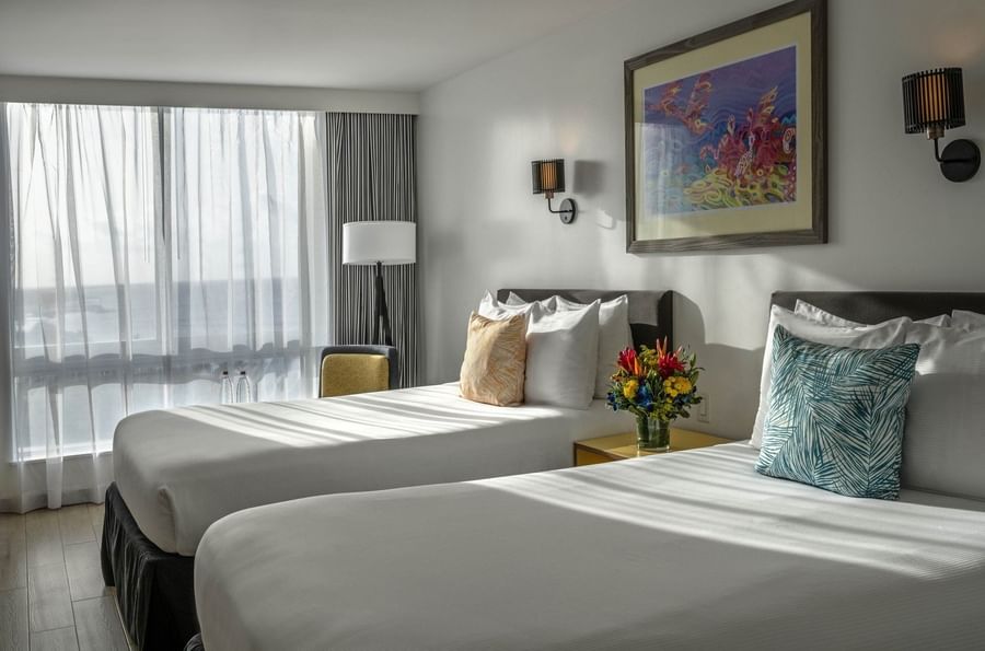 Two beds by a central nightstand under wall sconces in water view at Warwick Paradise Island Bahamas
