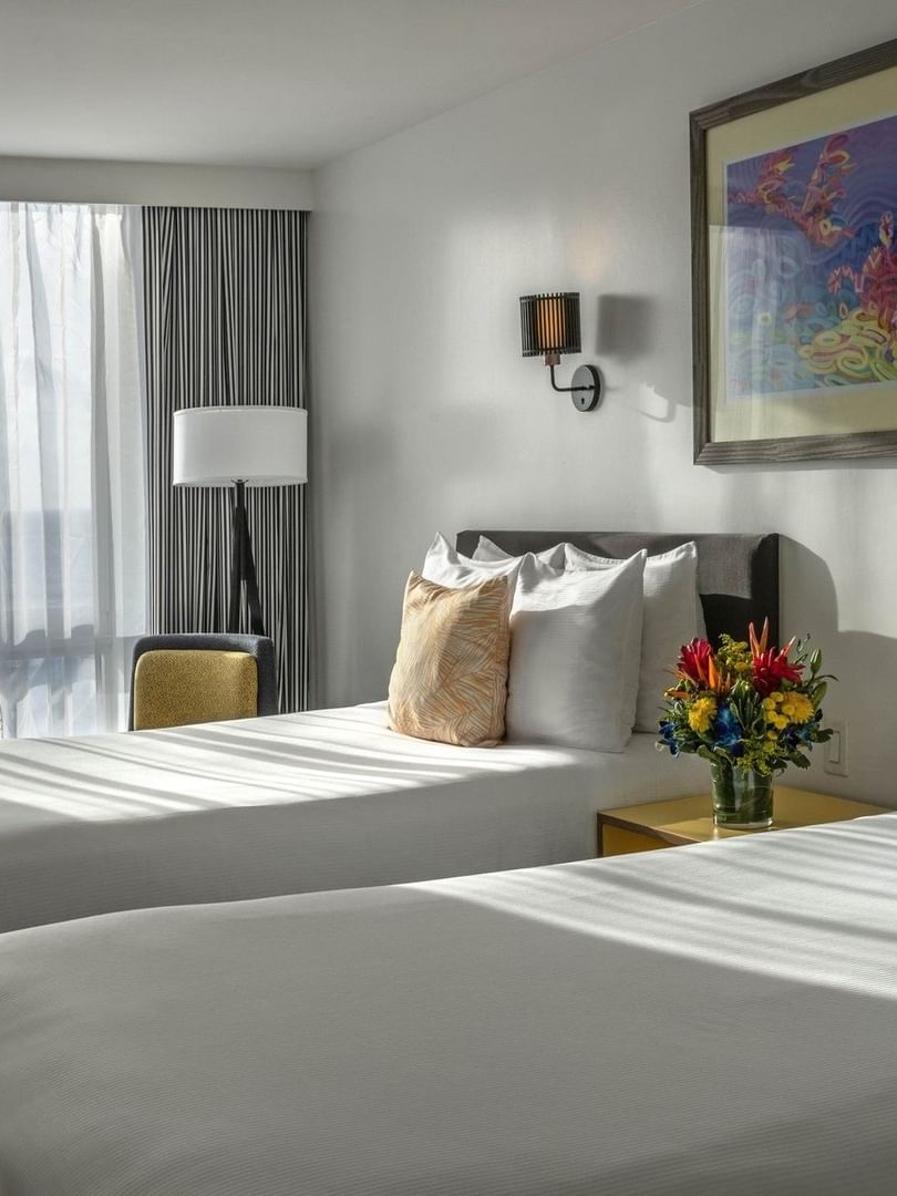 Two beds by a central nightstand under wall sconces in water view at Warwick Paradise Island Bahamas