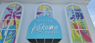 Logo of Kokomo Suites framed by vibrant tropical themed stained glass windows