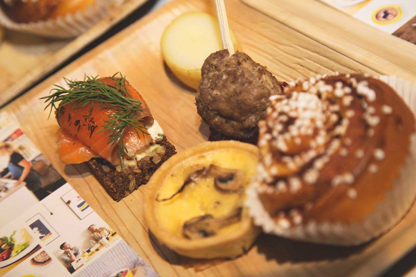 Fika Manly at Elysium Hotels has salmon rye toast beside a small quiche and meatball with a sweet cinnamon roll