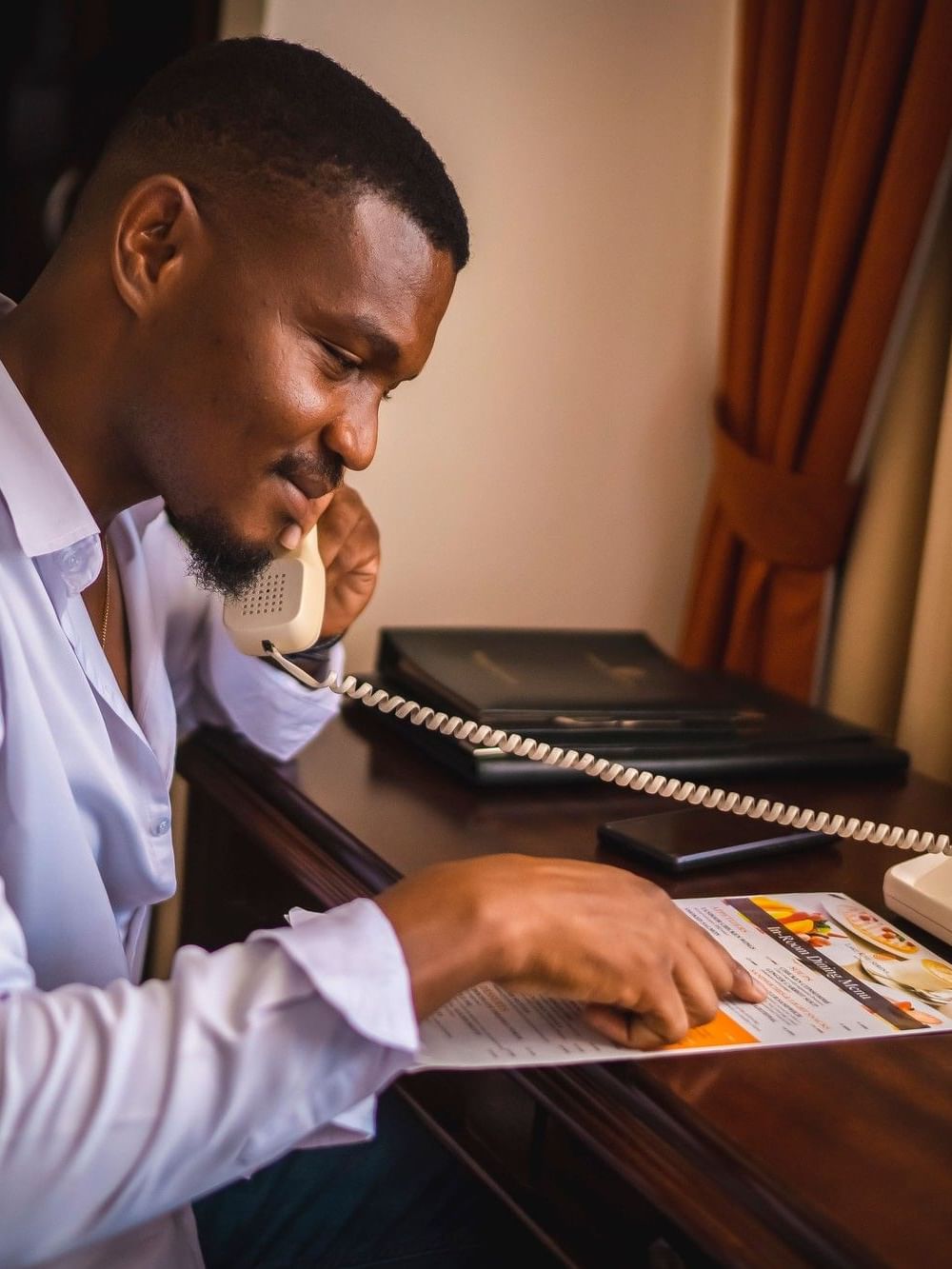 Man making a room service order by phone at Lake Kivu Serena Hotel in Gisenyi.